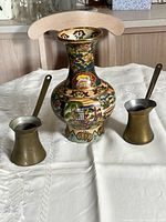 Front view of enamel vase flanked by two brass cups