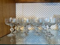 Group of etched coupe glasses on shelf