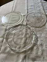 Three clear glass serving plates laid out on tablecloth