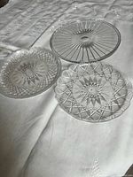 three clear round platters with differing pressed patterns