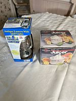 Front view of both boxed items: Olde Brooklyn lantern and West Bend juicer