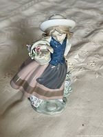 Front view of Lladro farm girl figurine showing outfit, basket of flowers and base