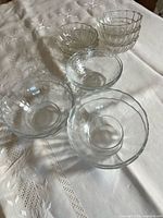 All twelve clear glass bowls grouped on tablecloth showing patterns and sizes