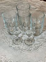 Three stacks of tumblers and two stemmed glasses on lace tablecloth