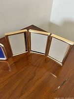Gold-tone hinged triple wallet frame on tabletop