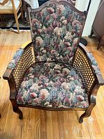 Full view of one chair showing wood frame, tapestry upholstery, cane sides, cabriole legs