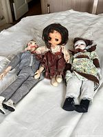 Front view of three dolls lying on bed