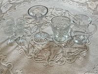 Full group of seven lead crystal barware pieces on lace tablecloth