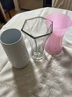 Three of the four vases: white textured ceramic, clear hexagonal glass, pink glass