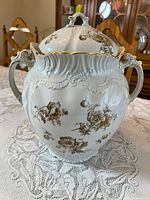 Front view showing entire lidded urn, handles, floral pattern