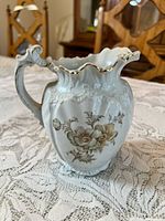 Front view showing floral design, fluted body, gilded rim and handle