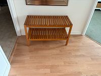 Full view of wooden slat bench against wall showing overall design and dimensions context