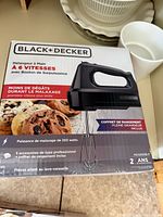 Box showing Black+Decker MX3200B-F 6-speed hand mixer and accessories