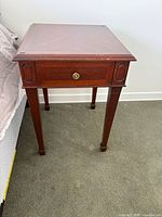 Full view of square solid wood accent table showing drawer, legs, and top