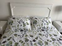 Front view of white wooden headboard attached to double bed