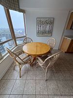 Overall view of round wood table with four rattan chairs