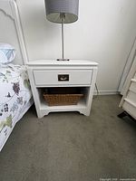 Front view of one nightstand showing drawer, brass pull, open shelf