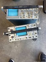 Top-down view of both Tektronix oscilloscopes showing model labels, screens, controls and handles