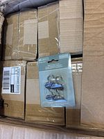 Cardboard shipping case opened showing multiple inner cartons and one Liberty magnetic hook retail package displayed
