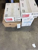 Stacked sealed boxes: two Fabri-Kal portion cup cases, one Premium Virgin toilet seat covers case, one Triple S bath tissue carton