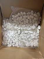 Open carton containing multiple clear bags filled with white inline thumb switches