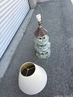 Full view of lamp body, harp, CFL bulb and detached damaged shade on ground