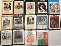 Front view of all 14 8-track tapes laid out in four-by-row grid, labels visible