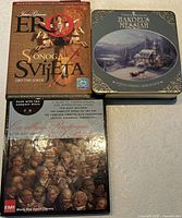Front view of three boxed sets: Ero S Onoga Svijeta, Thomas Kinkade tin, Cavalleria Rusticana & Pagliacci book