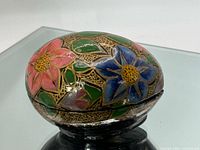 Side view of closed egg trinket box showing floral artwork