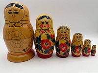 Front view of all six dolls showing painted faces and floral design