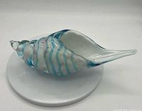 Profile view of glass conch shell showing blue and white stripes and clear tip
