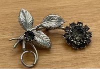 Full view of floral silvertone brooch on wood surface