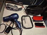 Group shot of all items laid out: hair dryer, three bags, clear Globe Gear pouch, eyeglass cases