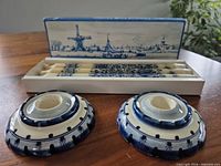 Two Delft ceramic candle holders and open box showing three Delft-patterned taper candles