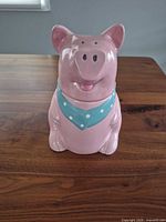 Front view of pink pig ceramic cookie jar with blue polka dot bandana