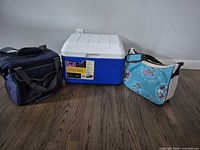 Three coolers: blue/white hard Coleman, navy duffel CI Sport, turquoise Coleman shoulder bag