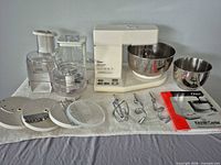 Full lot overview showing mixer base, bowls, attachments, processor, blender, manual