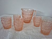 Set overview: pitcher with five tumblers in pink pressed glass