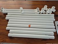 Group of white PVC tubes, base sections, and elbow connectors laid on table