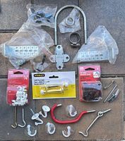 Overall lot showing packaged staples, doorstop, brackets, U-bolt, clamps, assorted hooks