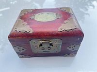 Closed jewelry box showing wood exterior, brass hardware, green stone inlay