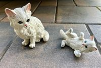 Both ceramic cat figurines on floor showing overall size and poses