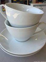 Stacked view of two white porcelain cups on two saucers