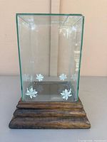 front view of glass display box showing floral motifs and wood base