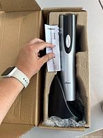 Electric wine opener seated in molded carton with charging base and packaging