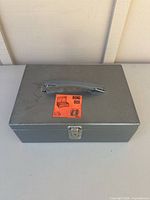 Closed gray steel cash box with handle and Bond Box label