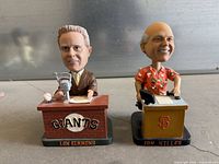 Front view of both bobbleheads showing figures, desks, nameplates and Giants branding