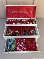 Full view of open three-tier jewellery box with assorted contents