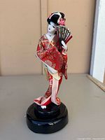 Full view of geisha figurine in red kimono on black base