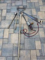Full lot showing rake, loppers, hedge trimmer, hand saw